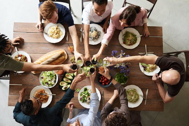 A group of people clink their glasses together over a table laden with food
