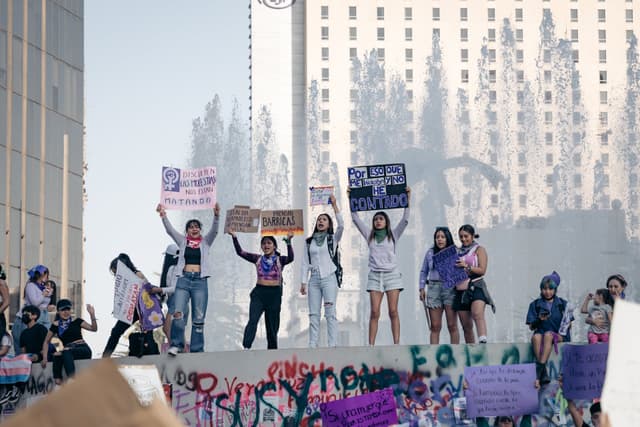 Women hold signs with hand-written slogans at a political demonstration