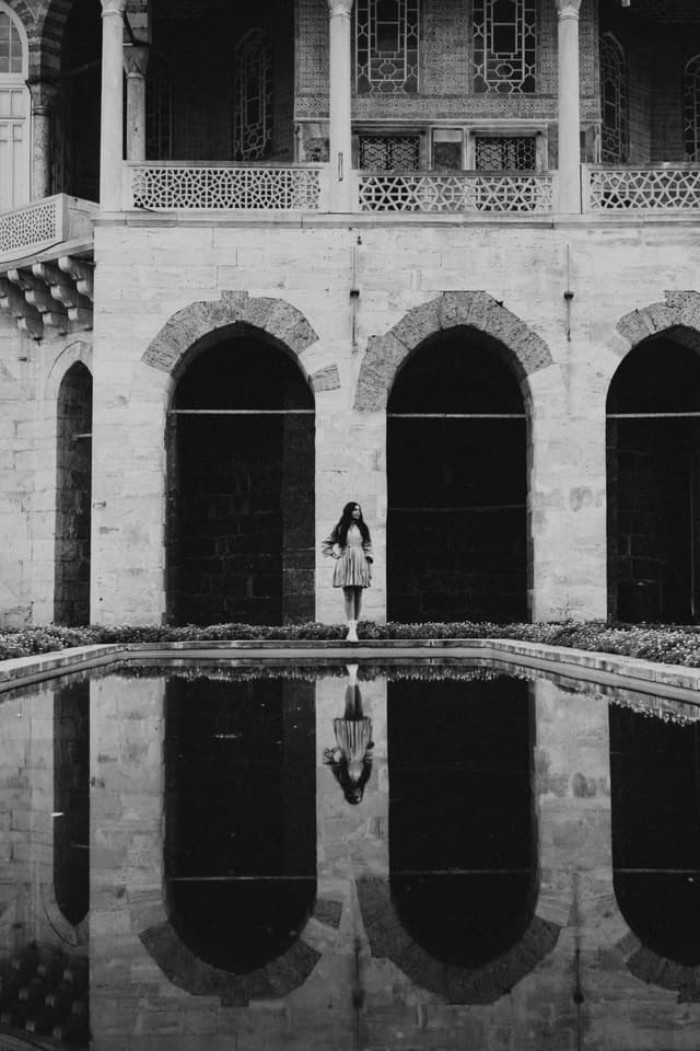 Black and white photo of a woman in front of a reflecting pool in Topkapi Palace