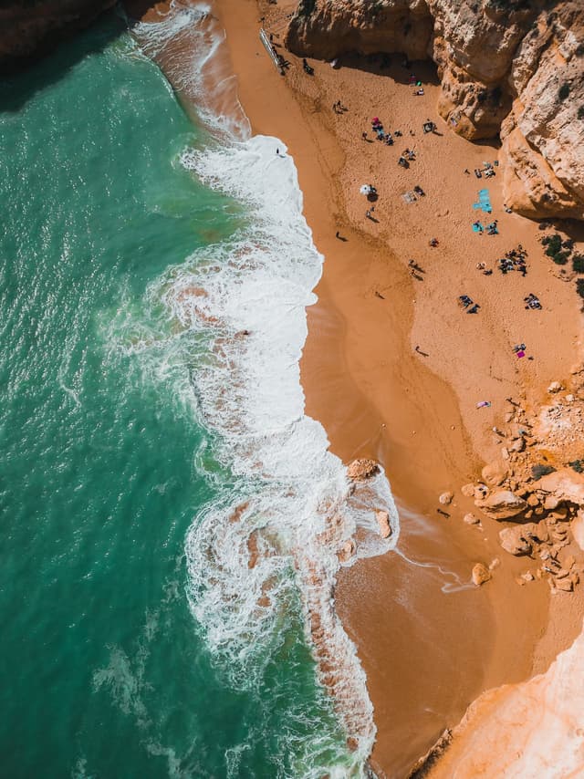 Birds-eye-view picture of a cove with water on the left and sand and cliffs on the right