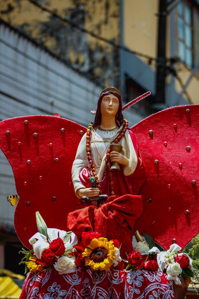 Decorated statue of Mary being held aloft in a parade