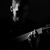 Black and white photo of a man playing an acoustic guitar